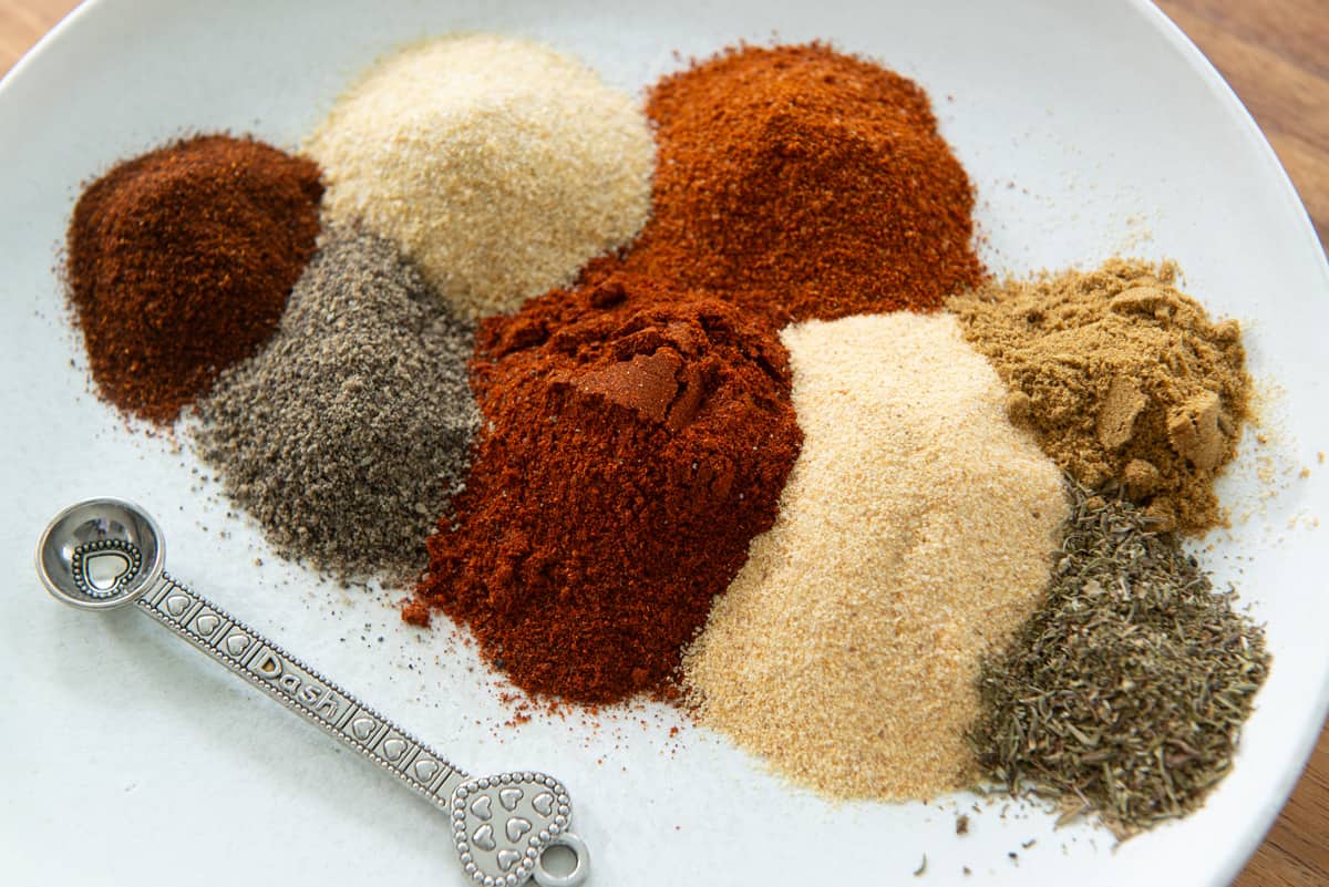 Spoonfuls of dry spices for pork rub recipe on a plate