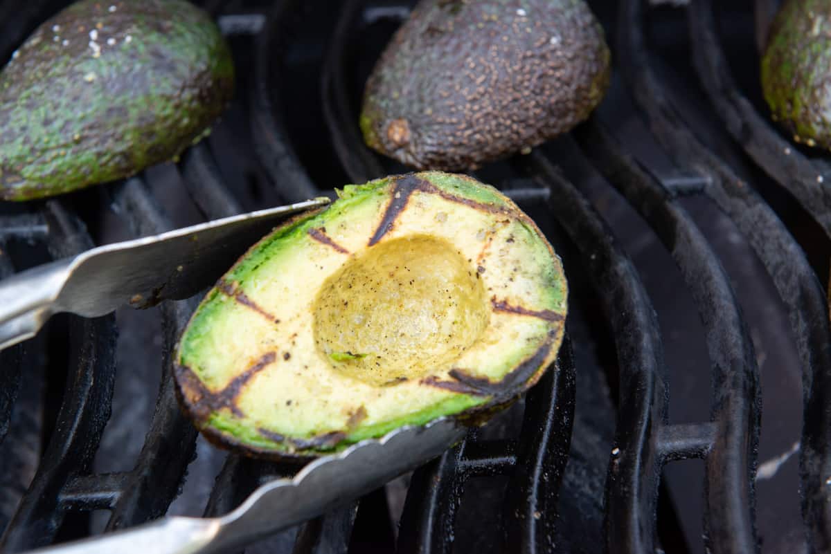 Tongs Showing A Fully Grilled Avocado Half