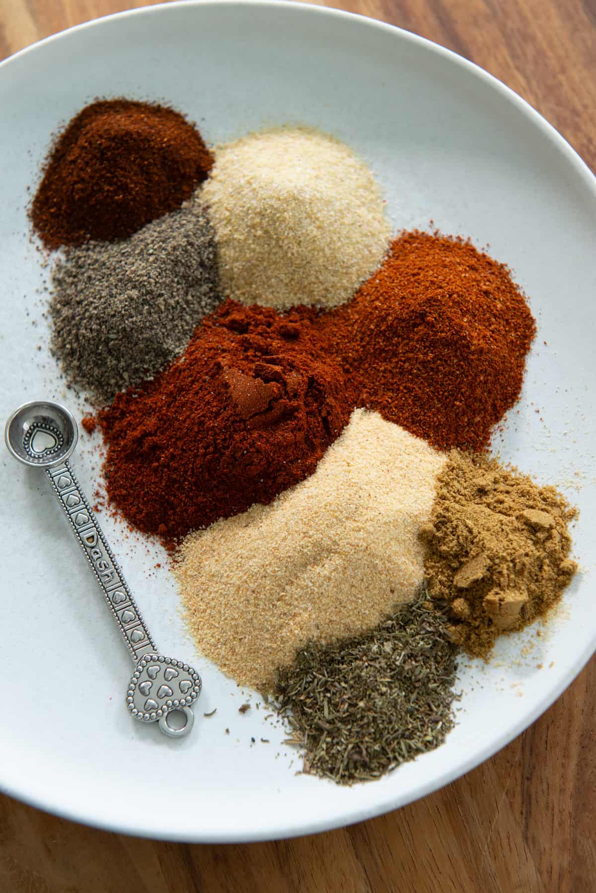 Spoonfuls of various spices and herbs on a plate