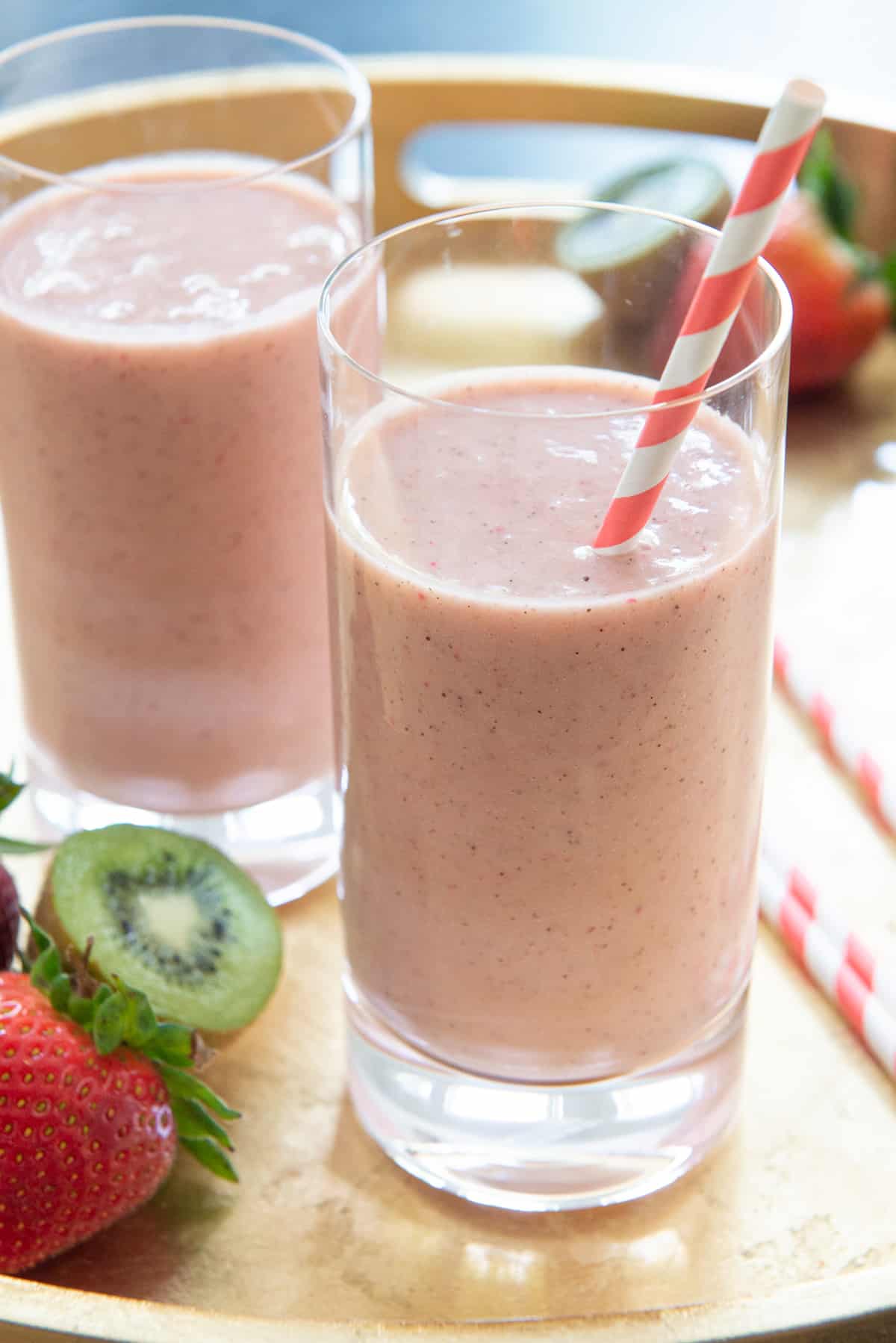 Strawberry kiwi smoothies in highball glasses on gold tray