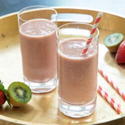 Strawberry Kiwi Yogurt Smoothies on a gold tray with red striped paper straws