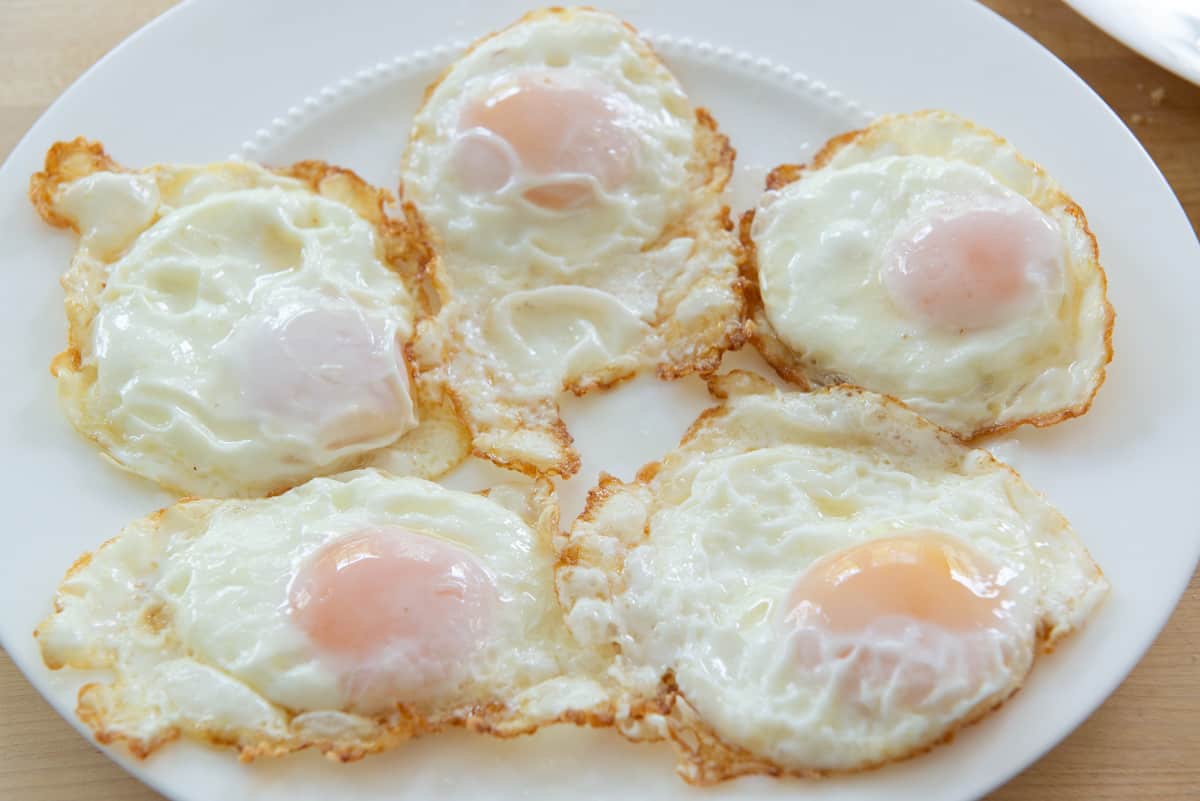 A plate of five basted eggs with crispy edges