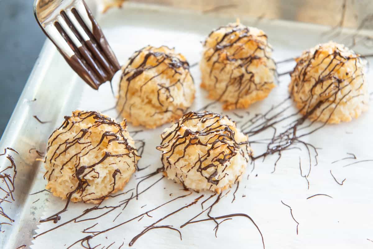 Drizzling Coconut Macaroons With Melted Chocolate Using Tines Of Fork