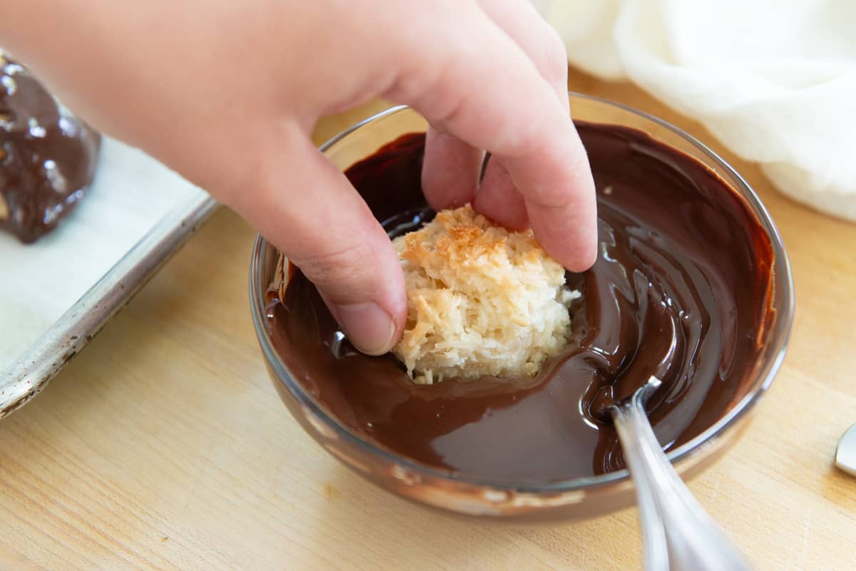Dipping Macaroon Cookie Into Melted Chocolate In Bowl