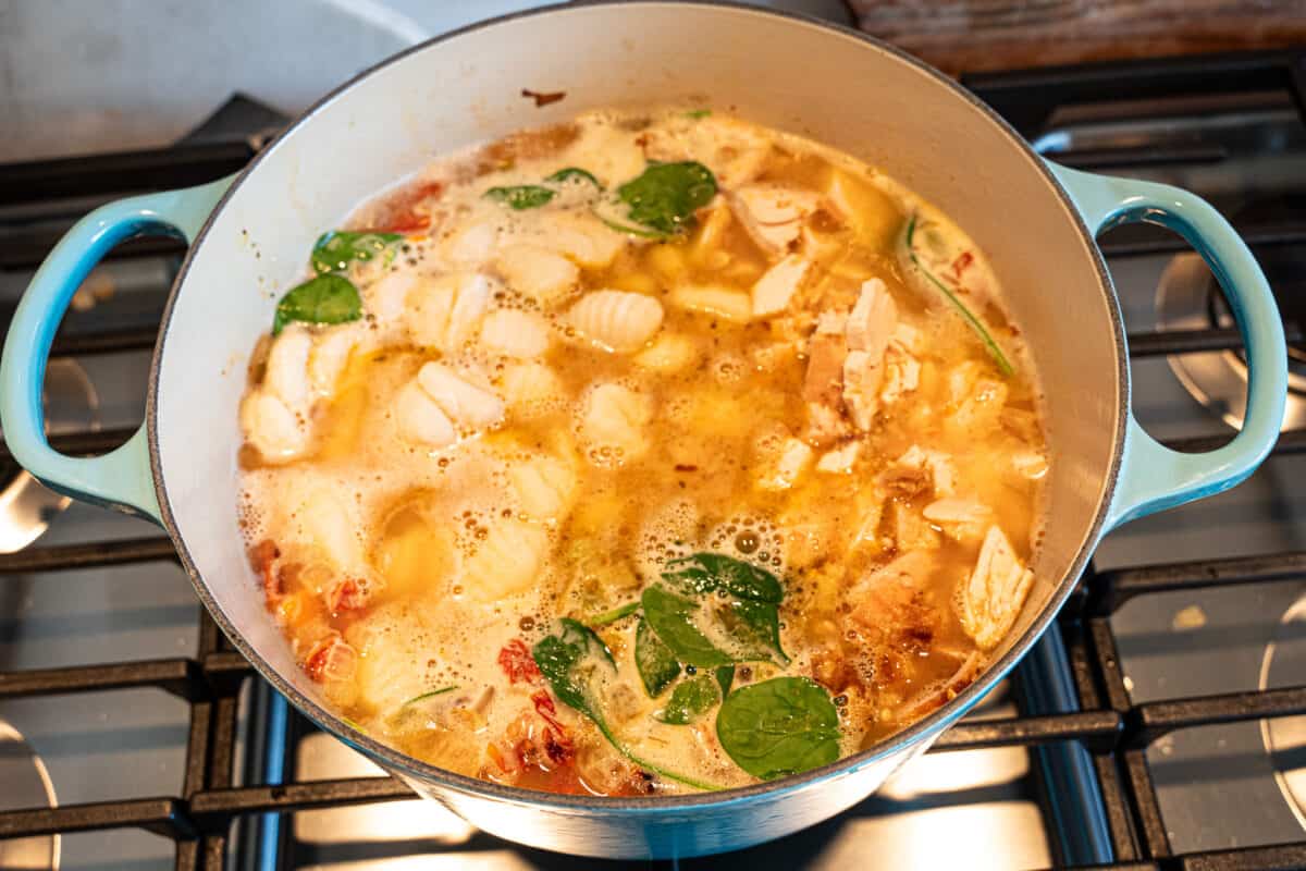 Chicken gnocchi soup simmering on stove in a pot