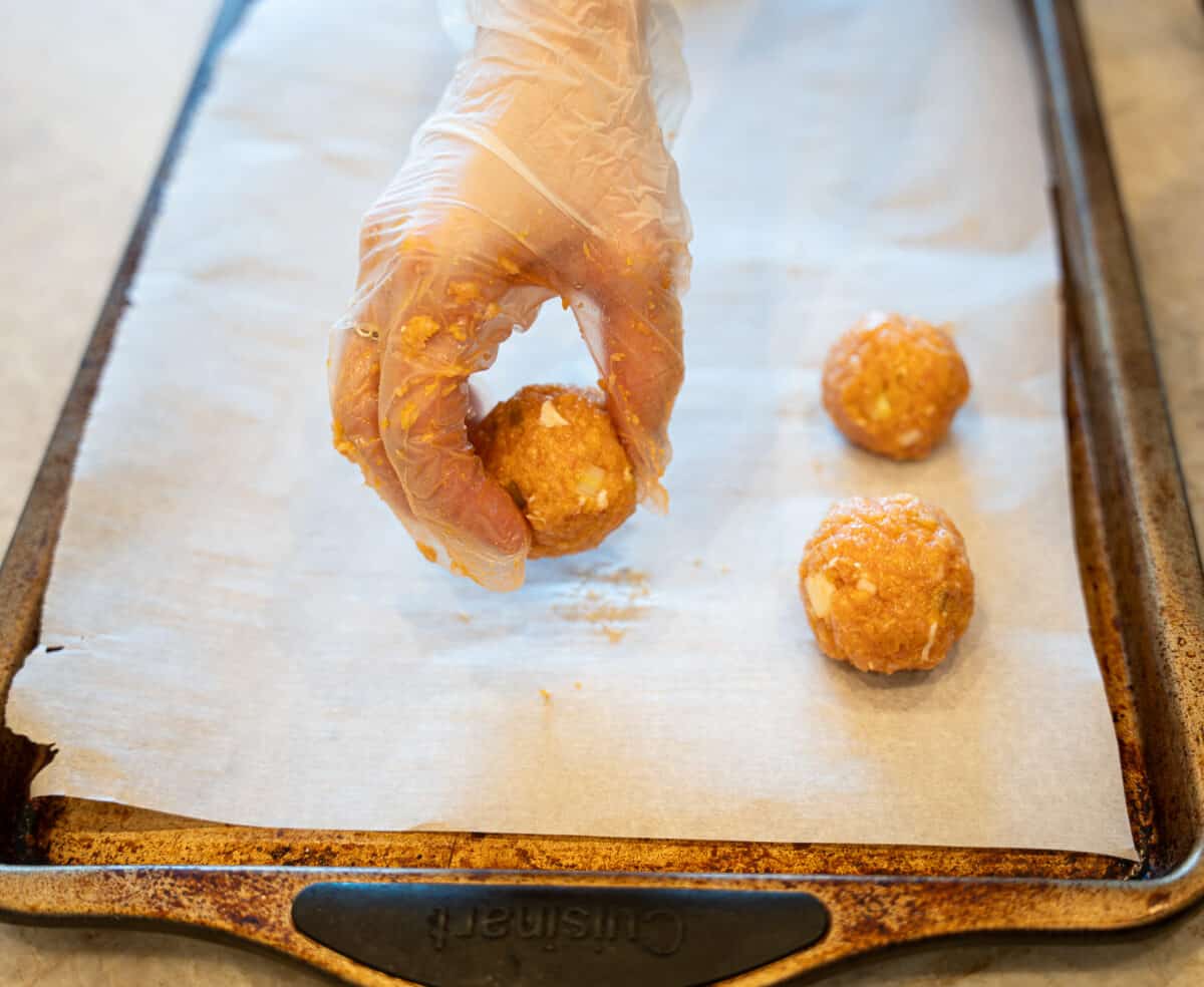 placing buffalo chicken meatballs on baking sheat