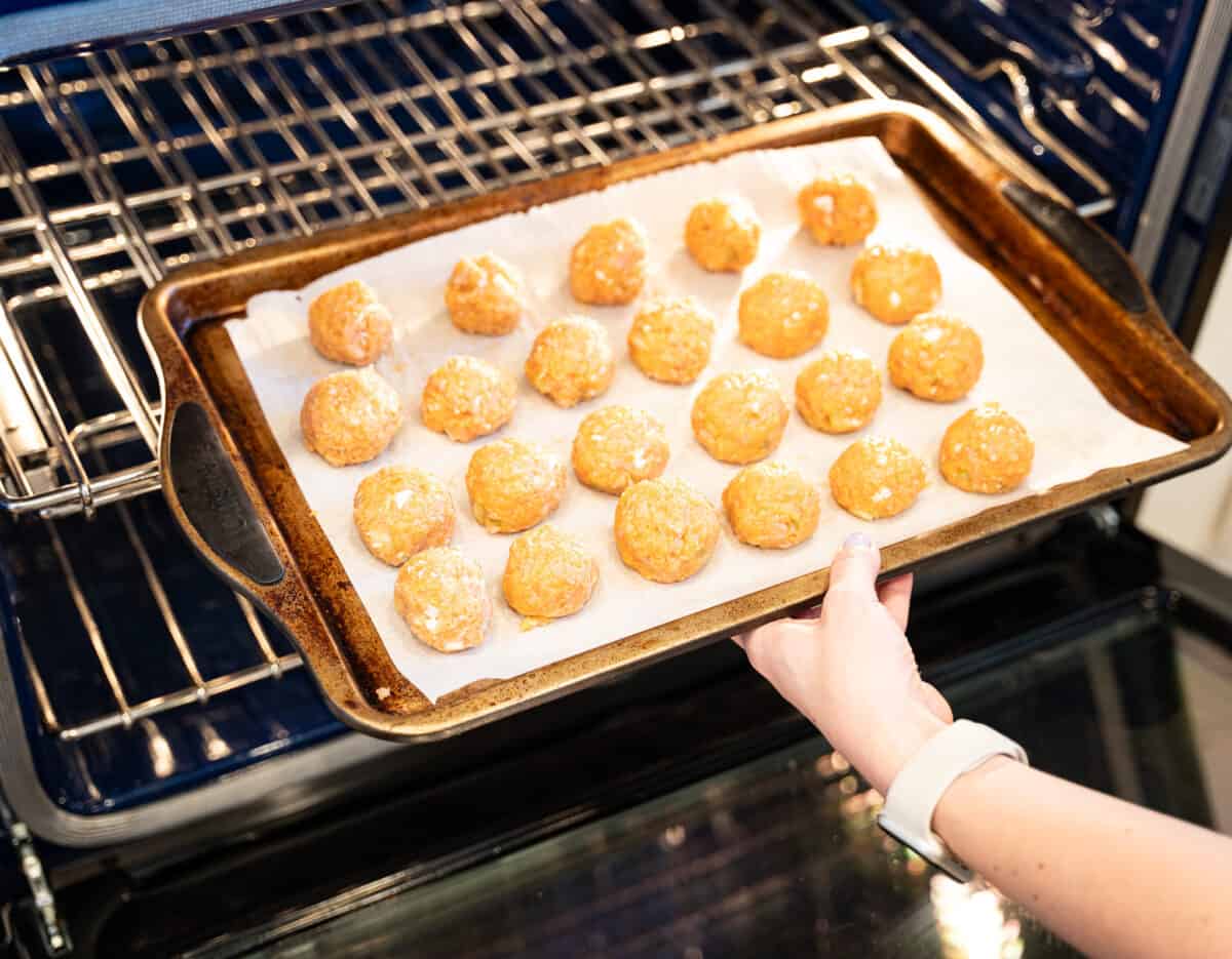 placing baking sheat of buffalo chicken meatballs into oven