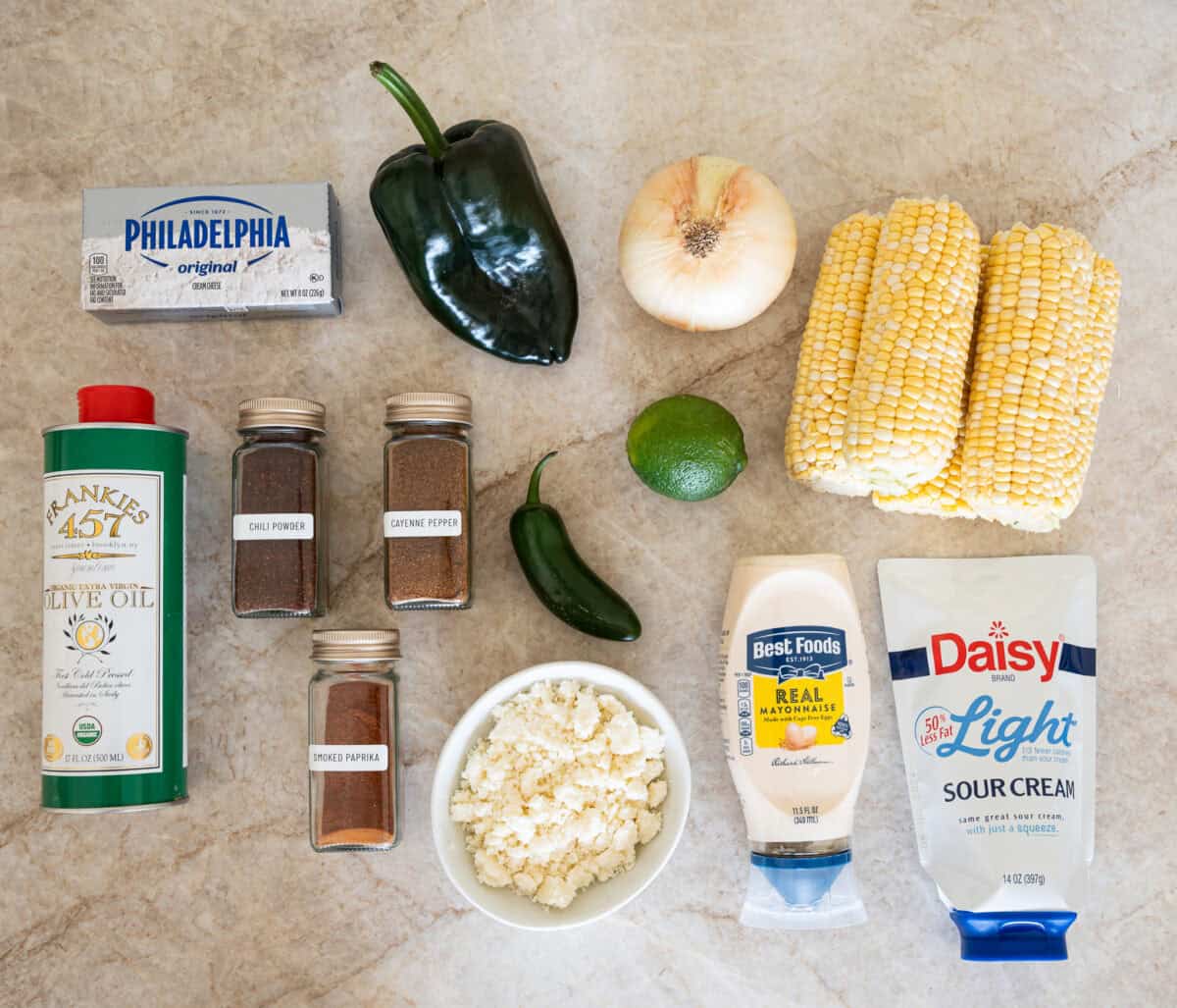street corn dip ingredients, olive oil, cream cheese, chili powder, cayenne pepper, smoked paprika, pablano pepper, jalapeno, lime, onion, cotija cheese, lime, corn, mayonnaise, sourcream