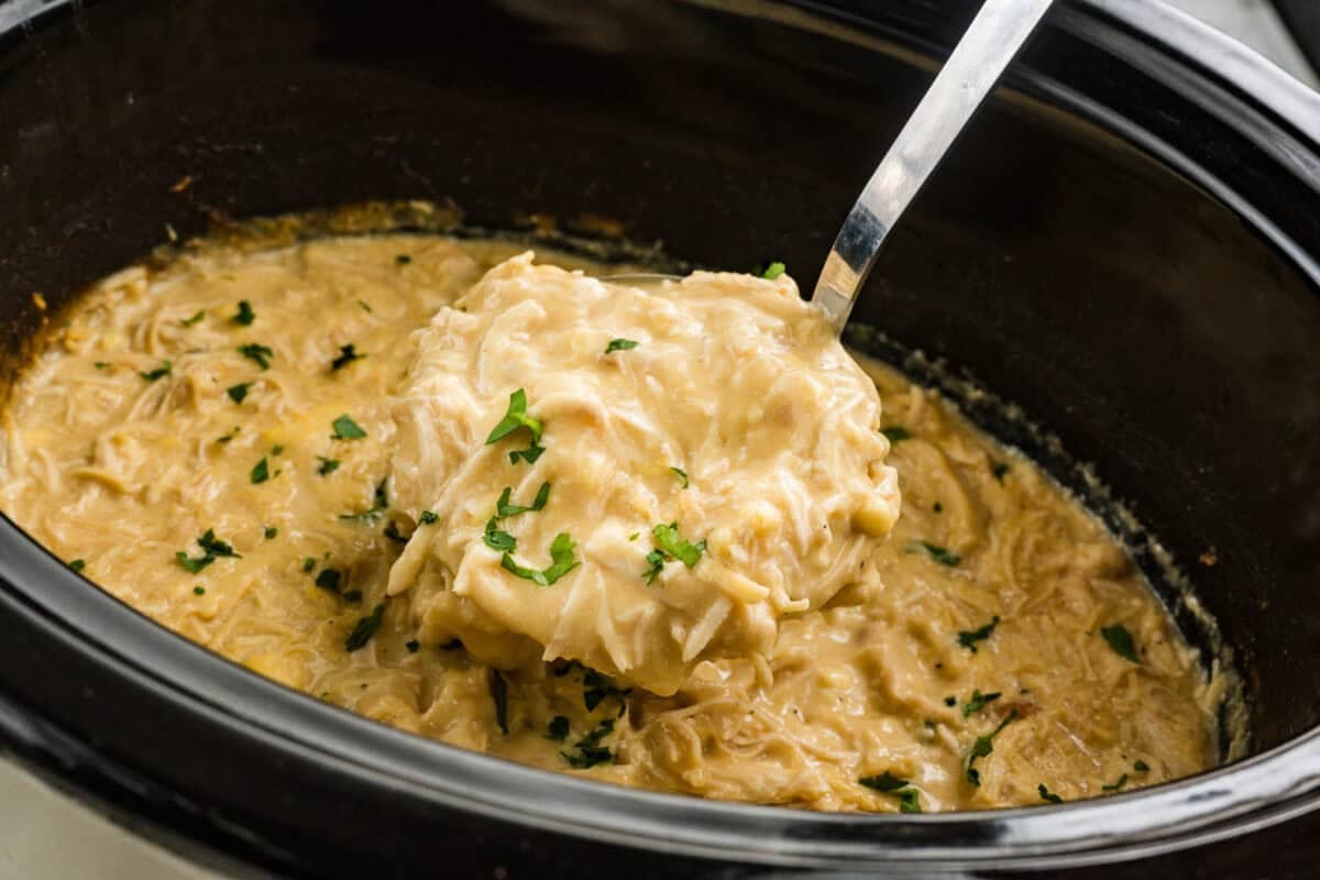coocked chicken and gravy in crock pot with ladle
