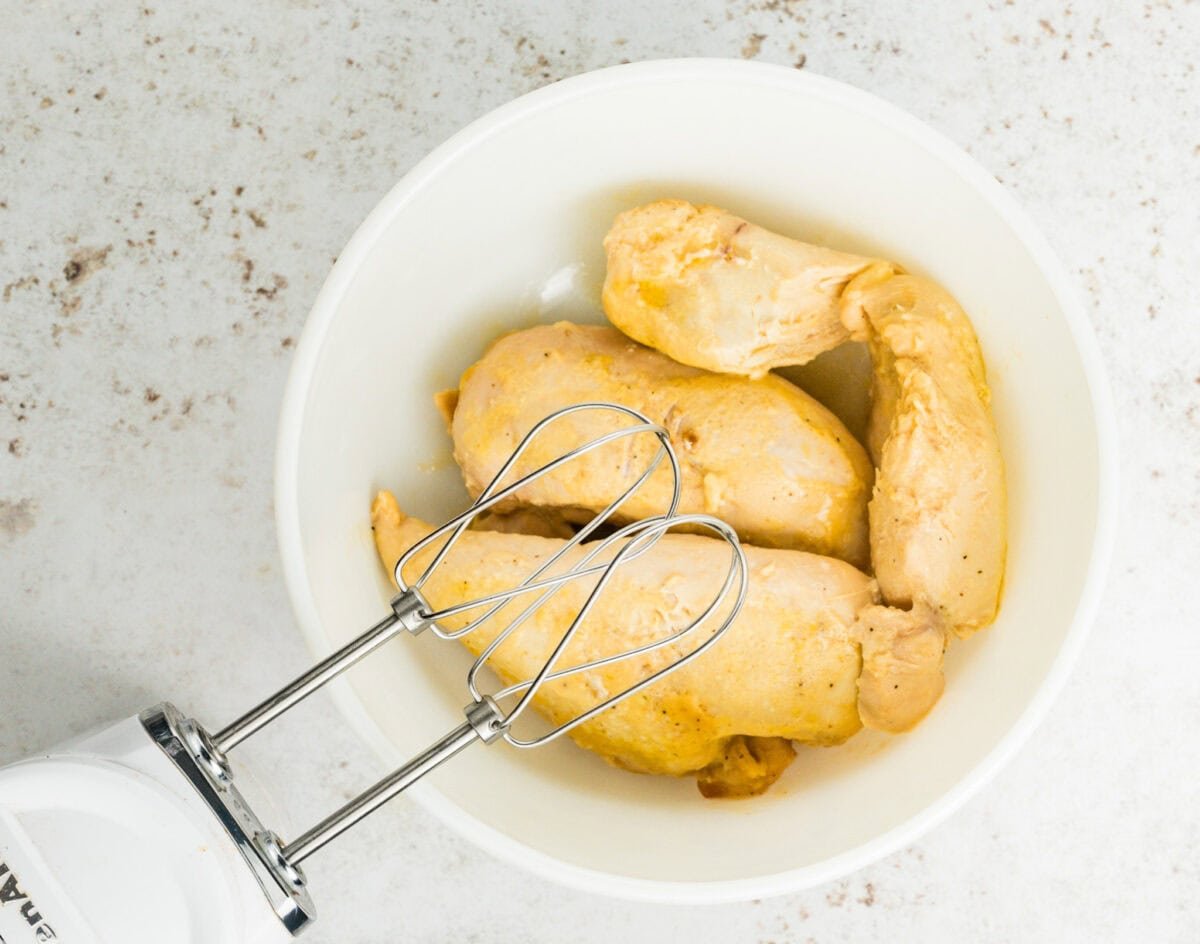 cooked chicken in bowl with mixer