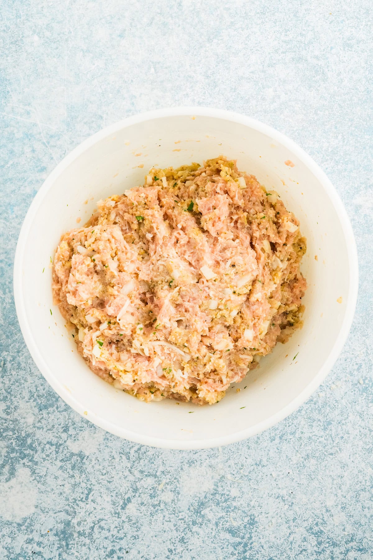Mix for parmesan chicken meatloaf combined in a white bowl.