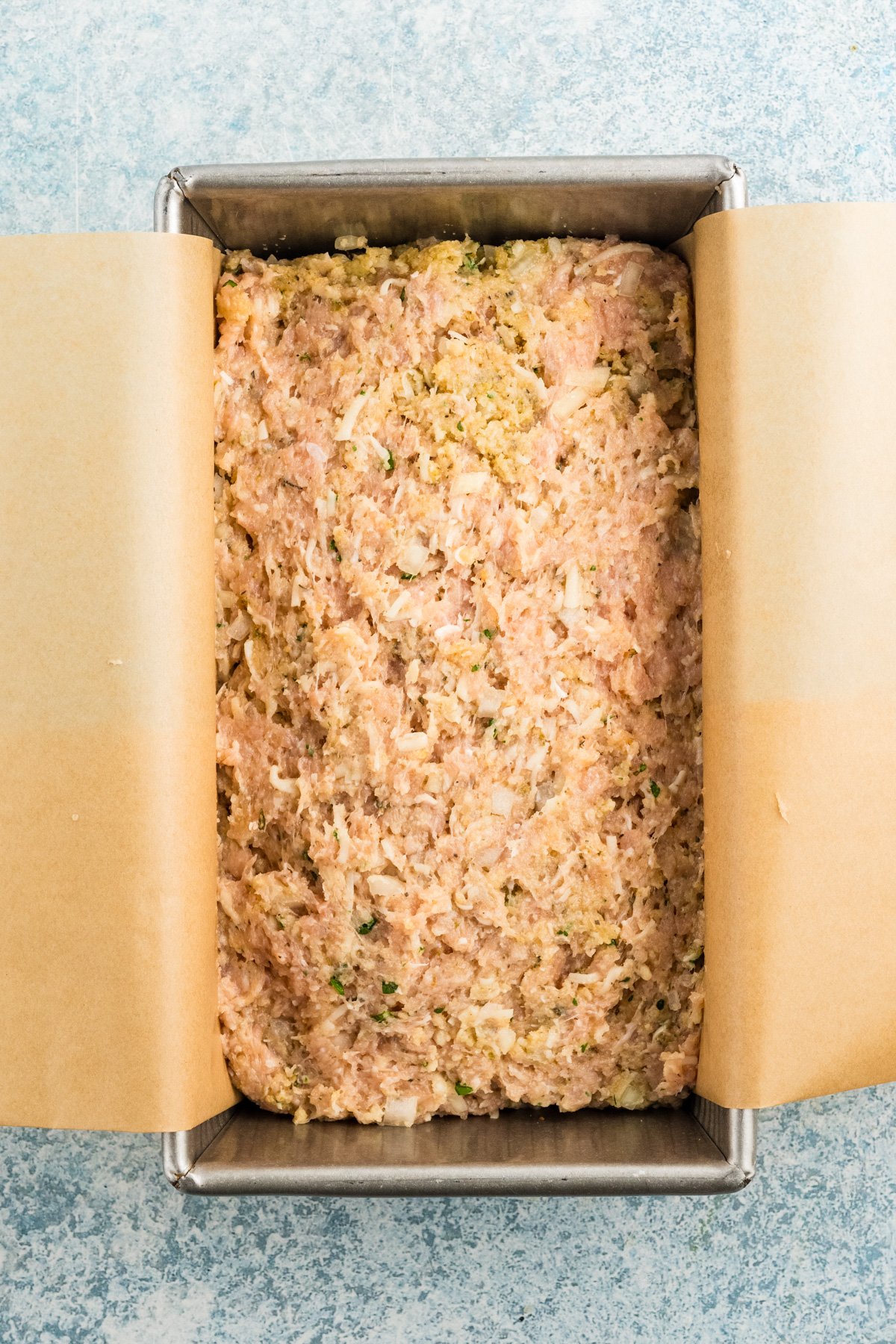 Mix for parmesan chicken meatloaf packed into a loaf pan, ready to go in the oven.